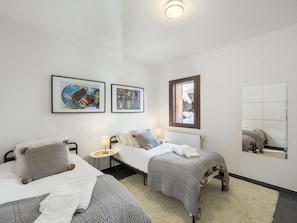 Ein Hotelzimmer mit zwei Betten, einem kleinen Tisch, einem Spiegel und Kunstwerken an den Wänden.