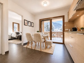 A modern interior with a dining area, kitchen, and a bedroom.