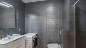 A modern bathroom with a built-in washing machine, a toilet, and a large mirror. - Modern, cosy 4-person flat - close to the centre and skiing (Châtel)
