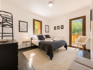 A bedroom with a bed, a chair, a desk, and a window.