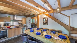 A modern kitchen with wooden beams, a dining area with blue plates, and a staircase. - Chalet 10 pers - large spaces, fireplace, quiet location (Châtel)