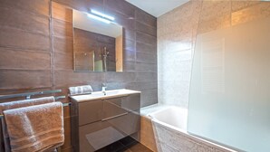 Ein modernes Badezimmer mit einem großen Spiegel, einem Waschbecken und einer Badewanne.