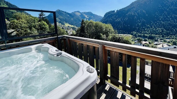 Ein Whirlpool auf einer Holzterrasse mit Blick auf die Berge.