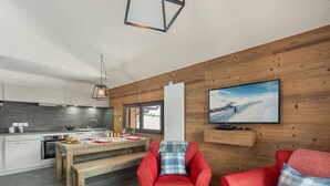 Eine moderne Küche mit Essbereich, roten Sofas und einem Fernseher an der Wand.