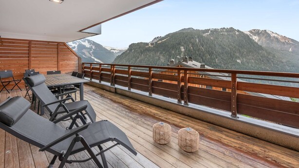 A wooden deck with outdoor seating and a view of mountains. - 4-person flat - fireplace, close to the centre and slopes (Châtel)