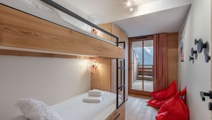 A bunk bed room with a wooden ceiling, a small balcony with a view of mountains, and a red bag on the floor. - 4-person flat - fireplace, close to the centre and slopes (Châtel)