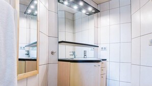 A modern bathroom with a large mirror, a sink, and a toilet. - 8-person flat in adjoining chalet, village centre, close to slopes (LA CHAPELLE D ABONDANCE)