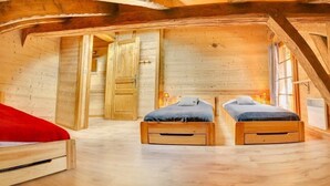 A wooden cabin with two wooden beds, a red sofa, and a large window. - 8-person flat in adjoining chalet, village centre, close to slopes (LA CHAPELLE D ABONDANCE)