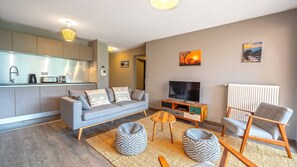 A modern living room with a grey sofa, a flat-screen TV, and a wooden coffee table.