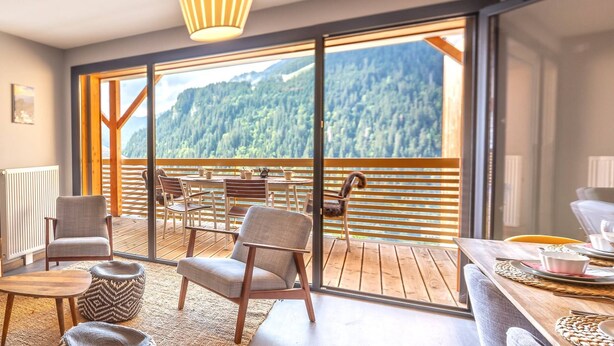 Ein modernes Zimmer mit einer großen Glasschiebetür, die auf einen Balkon mit Bergblick führt.