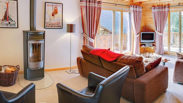 A cozy cabin interior with a fireplace, wooden furniture, and large windows. - Chalet 7 people - authentic chalet, close to the village (Châtel)