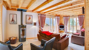 A cozy living room with a fireplace, comfortable seating, and large windows. - Chalet 7 people - authentic chalet, close to the village (Châtel)