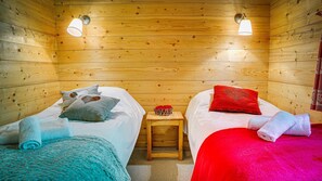 A cozy cabin room with two beds, a small wooden stool, and two wall-mounted lamps. - Chalet 7 people - authentic chalet, close to the village (Châtel)