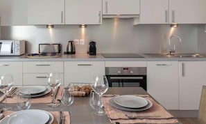 A modern kitchen with white cabinets, a microwave, toaster, kettle, and a dishwasher. - Apartment for 4 pp - top floor, modern, close to center and ski lifts (Châtel)