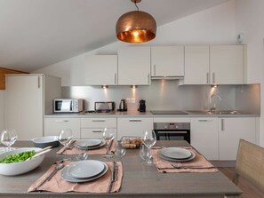 A modern kitchen with white cabinets, a stainless steel sink, and a dining table set for four. - Apartment for 4 pp - top floor, modern, close to center and ski lifts (Châtel)