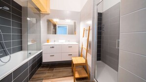 Un baño moderno con una bañera, un lavabo y una silla de madera.