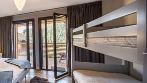 A bedroom with a bunk bed, a desk, and a large sliding glass door leading to an outdoor deck.