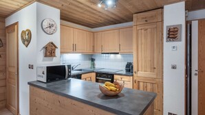 Cocina moderna con armarios de madera, microondas integrado y una isla grande con un frutero.