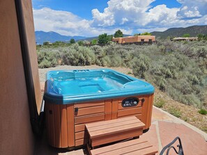 A hot tub with a control panel, wooden steps, and a view of a mountainous landscape.