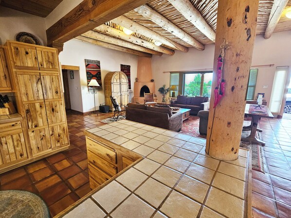 A spacious living room with a fireplace, wooden furniture, and a large window.