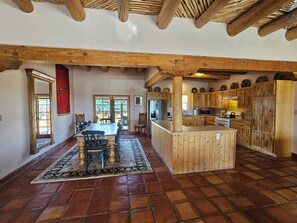A spacious kitchen with wooden cabinets, a central island, and a dining area with a table and chairs.