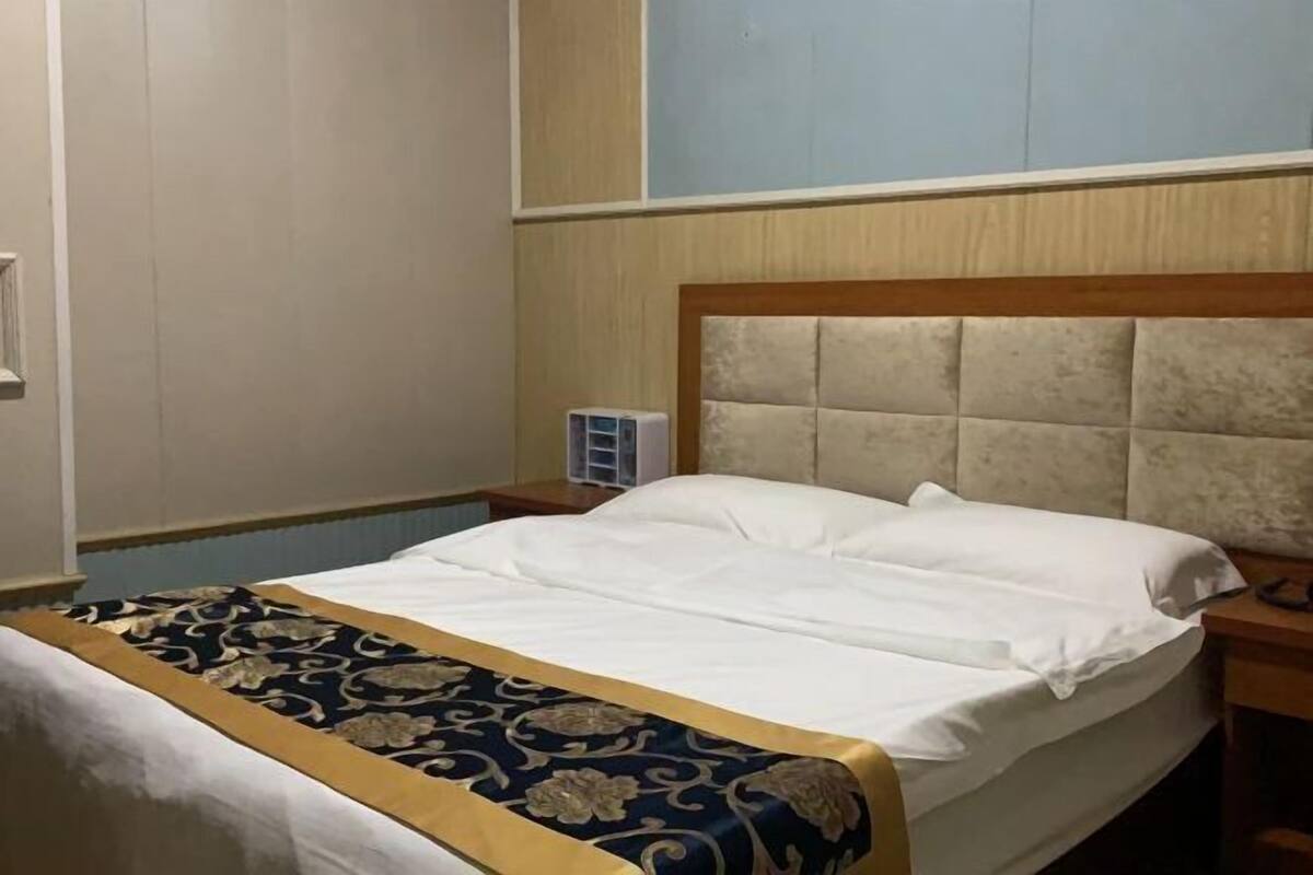 A hotel room with a bed, a nightstand, and a wall-mounted air purifier.