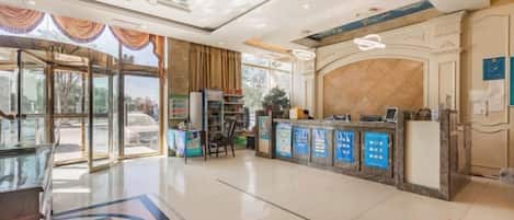 A hotel lobby with a reception desk, a glass partition, and a reception area.