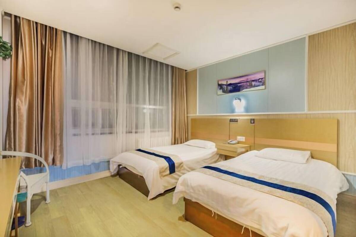 A hotel room with two beds, a desk, and a chair.