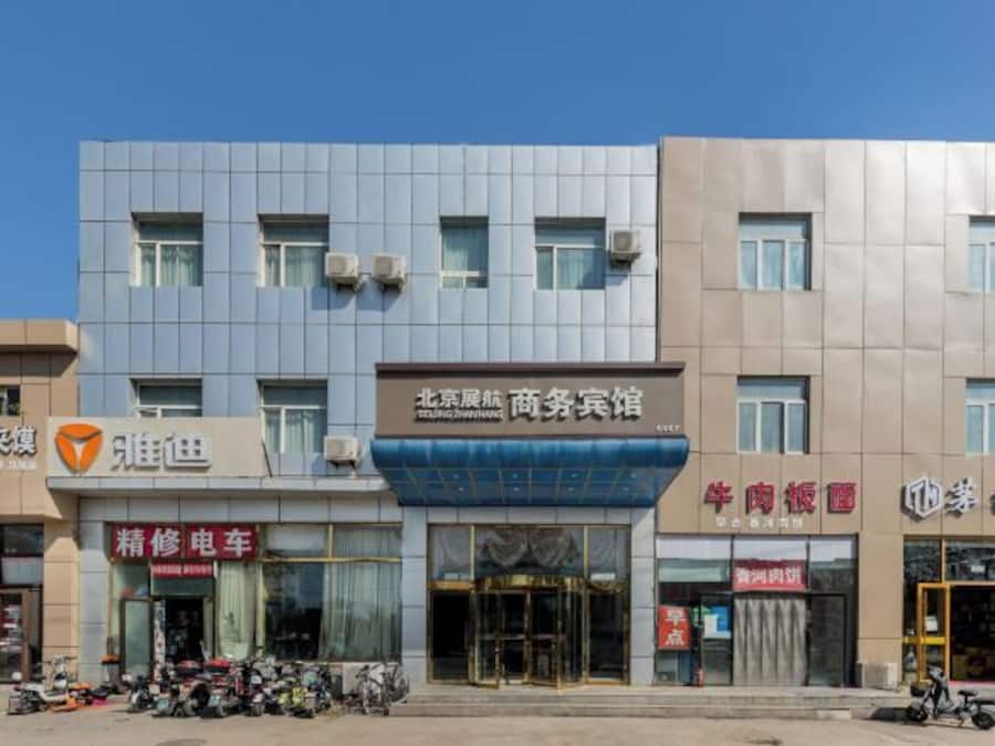 A multi-story building with commercial establishments on the ground floor, including a car repair shop and a business center.
