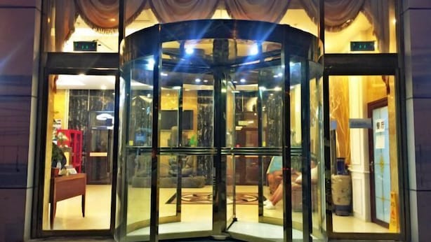 A revolving door with glass panels, leading to a lobby area with a red chair and a vase. - Zhanhang Business Hotel (Beijing Capital Airport New International Exhibition) (Beijing)