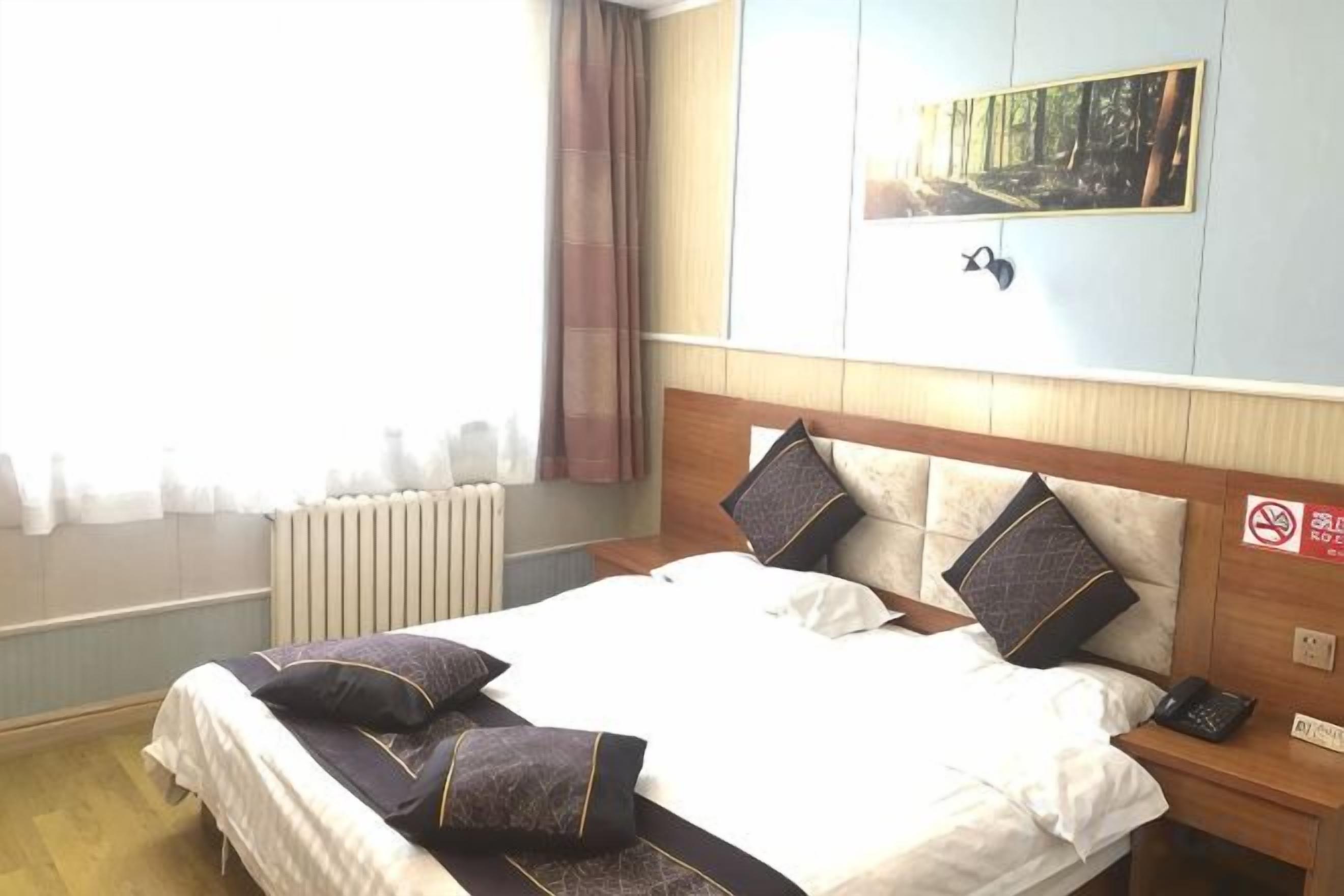 A hotel room with a bed, bedside table, and a view of the city.