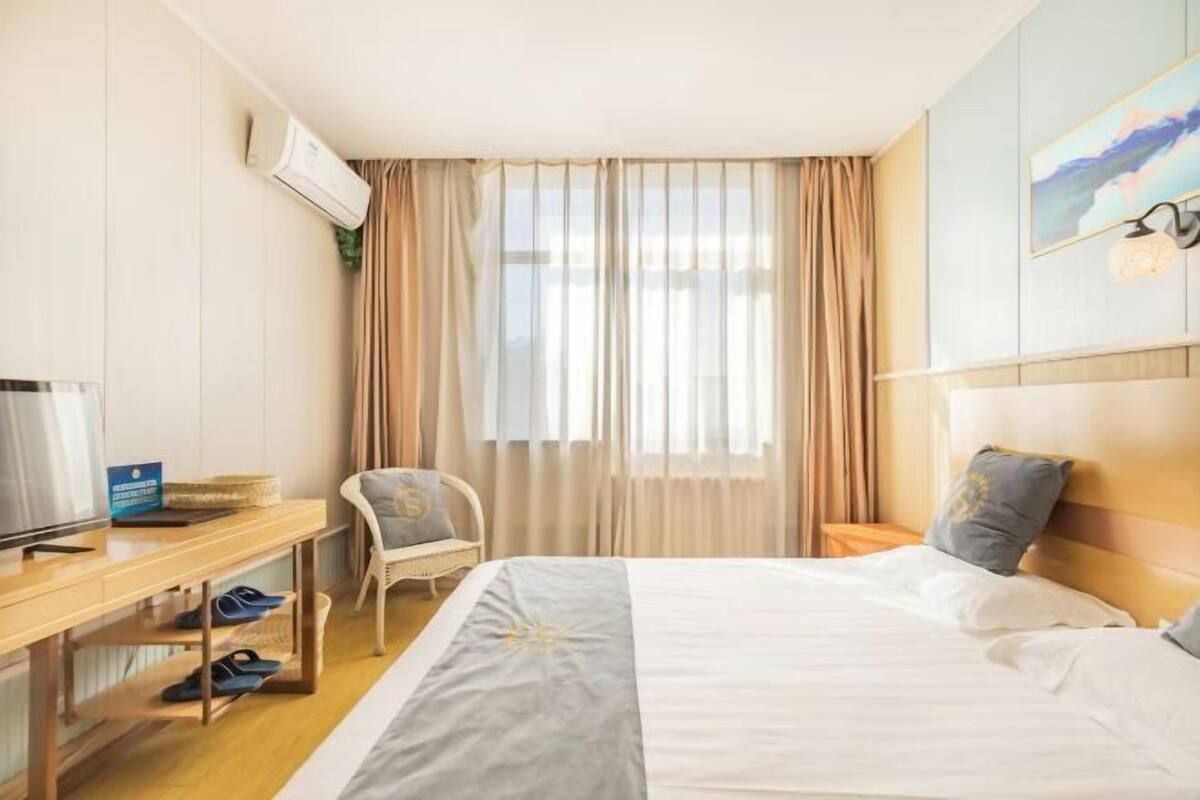 A hotel room with a bed, a desk with a computer, a chair, and a TV.