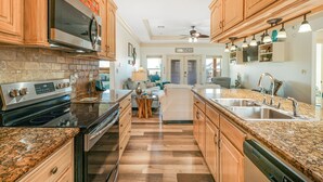 A modern kitchen with wooden cabinets, granite countertops, and stainless steel appliances. - Seaside MERRYment - 4 Bedroom + Bonus Room, 2 Bath, Sleeps 16. (Crystal Beach)