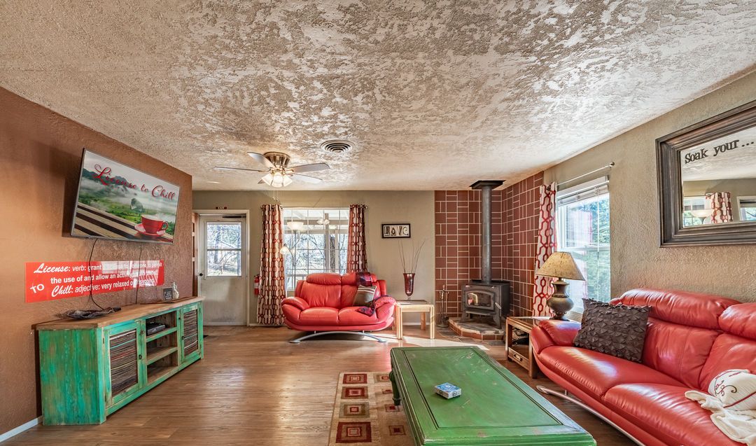 A living room with a fireplace, red leather sofas, a green coffee table, and a television mounted on the wall.