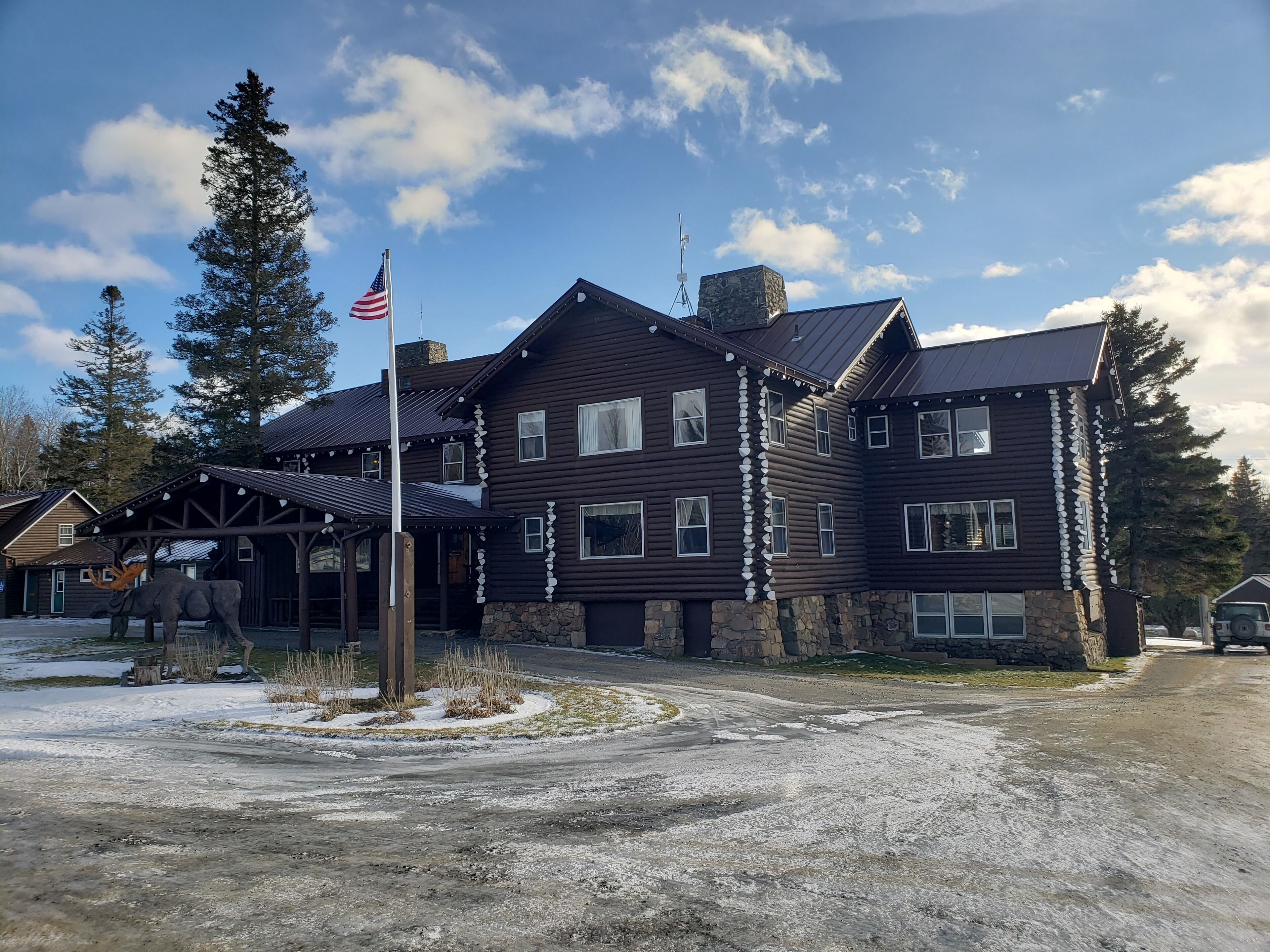 Un grand bâtiment de style chalet en bois, doté de nombreuses fenêtres et fondé sur une base en pierre.
