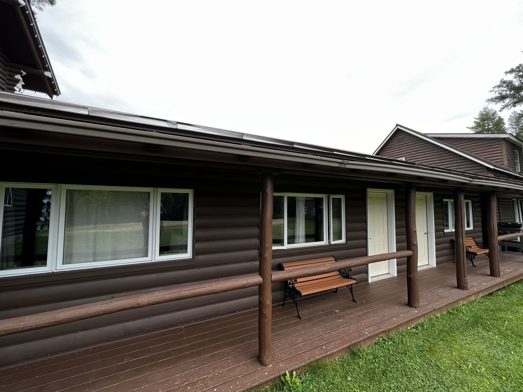 Une cabane en rondins avec une véranda, des bancs en bois et une pelouse.