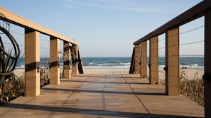 Una passerella di legno che conduce alla spiaggia, con vista libera sull'oceano.