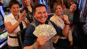 A group of people in a casino environment with slot machines and gaming tables.