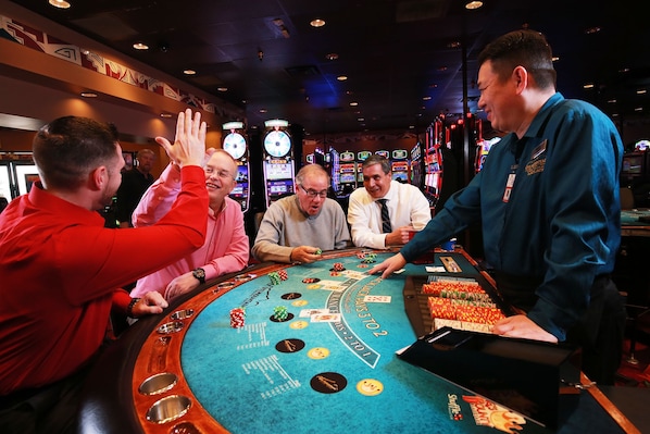 Una mesa de blackjack en un casino, con jugadores y un crupier.