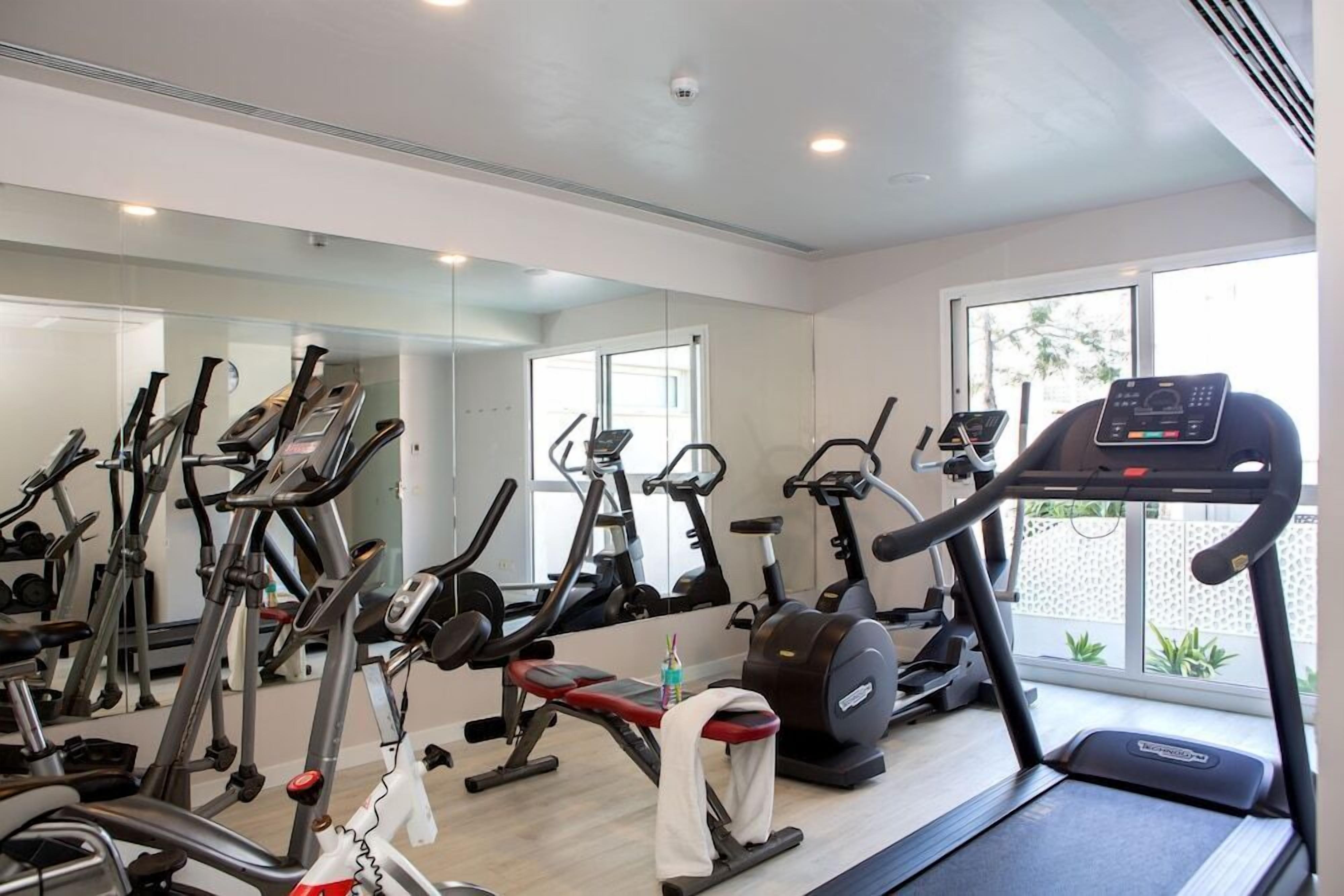 A gym with various exercise equipment, including treadmills, stationary bikes, and weight machines.