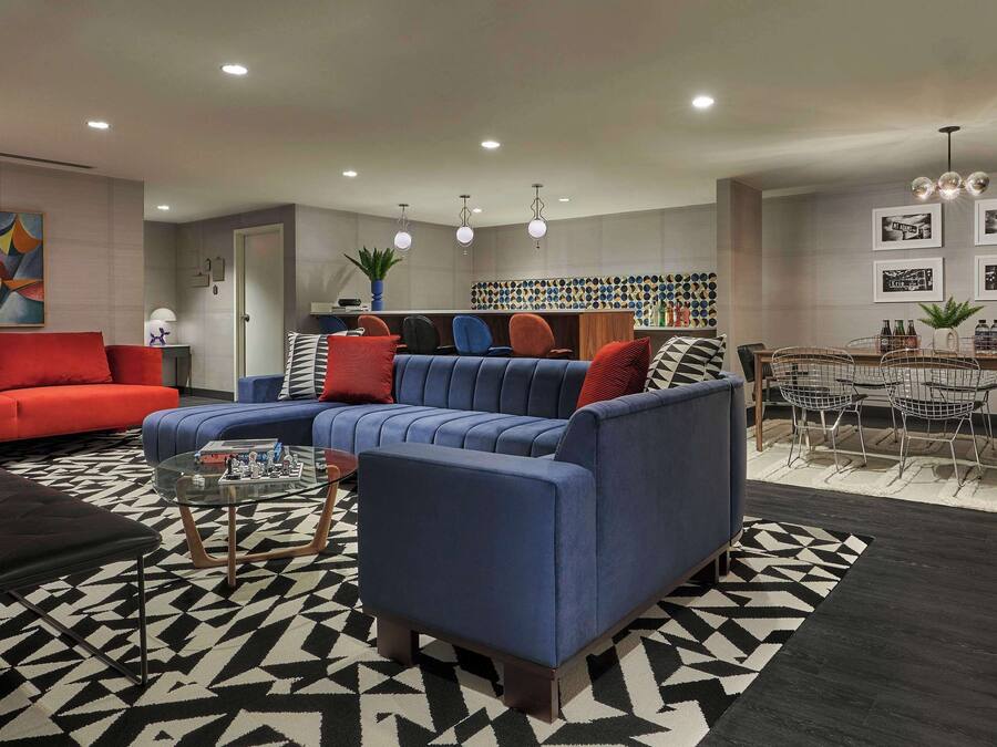 A modern living room with a sectional sofa, a coffee table, and a dining area with chairs and a table.