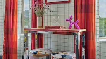 A room with a tiled wall, a table with a vase, books, and a balloon sculpture.