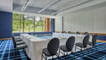 Une salle de conférence équipée d’une longue table, de chaises et d’un écran de projection.