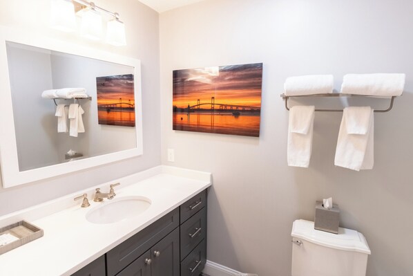 A bathroom with a large mirror, a sink, and two towels hanging on a rack.