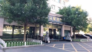 A hotel entrance with a gated driveway, a statue, and a building with a sign.