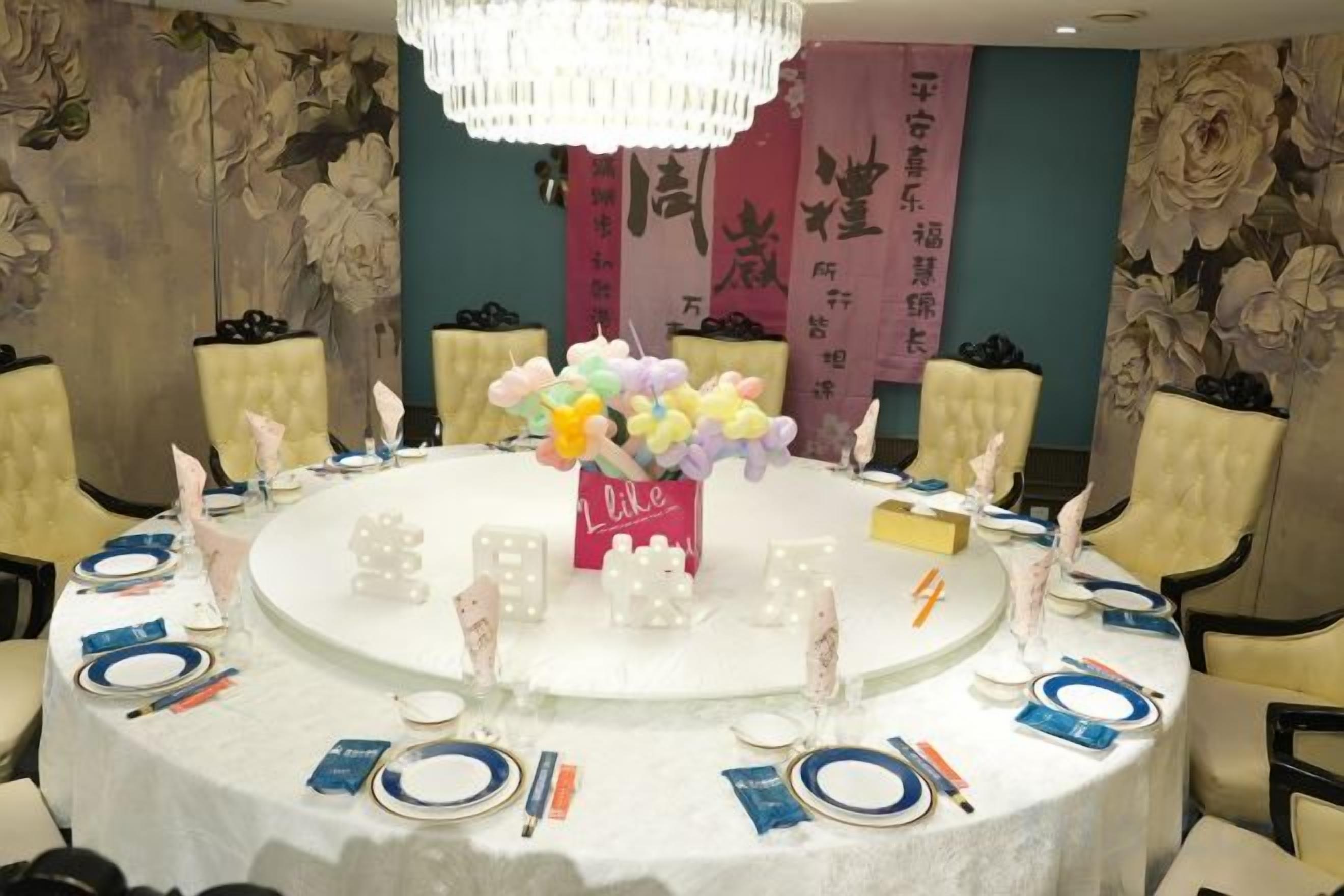 A round table set for a meeting with a floral centerpiece, white napkins, and blue plates.