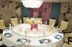 Una mesa redonda dispuesta para una reunión, con un centro de mesa floral, servilletas blancas y platos azules.