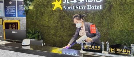 A reception desk at NorthStar Hotel with a green wall backdrop, a digital display, and a sign indicating the reception area.
