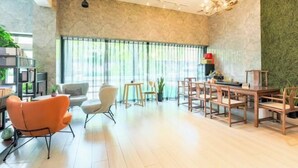 Ein modernes Wohnzimmer mit Essbereich, großen Fenstern und einer Wand mit Grüner Struktur.