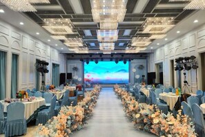 A banquet hall with rows of tables, a stage with a large screen, and a chandelier. - Northstar Business Linkage Hotel (Beijing)